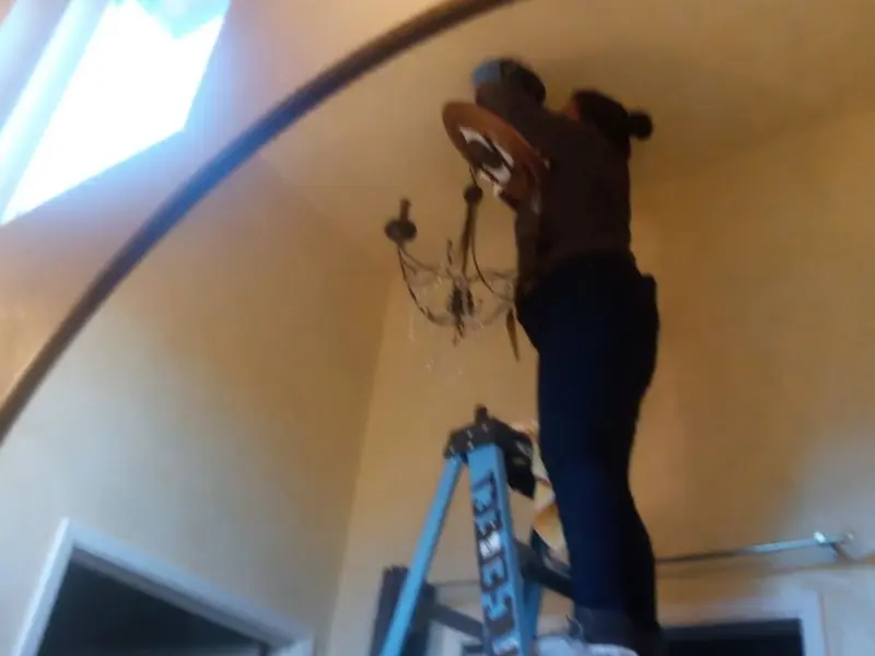 Electrician installing a chandelier in a Ivins residence